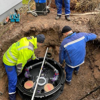 Drei OKO-tech Servicetechniker bauen eine Hebeanlage vom Typ Kessel Ecolift Duo in einen Schacht im Garten ein