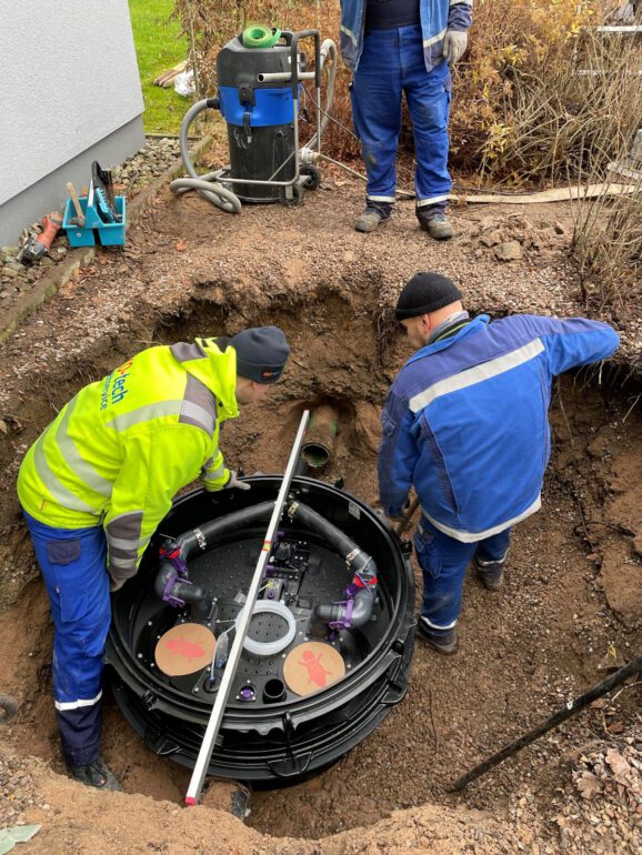 Drei OKO-tech Servicetechniker bauen eine Hebeanlage vom Typ Kessel Ecolift Duo in einen Schacht im Garten ein